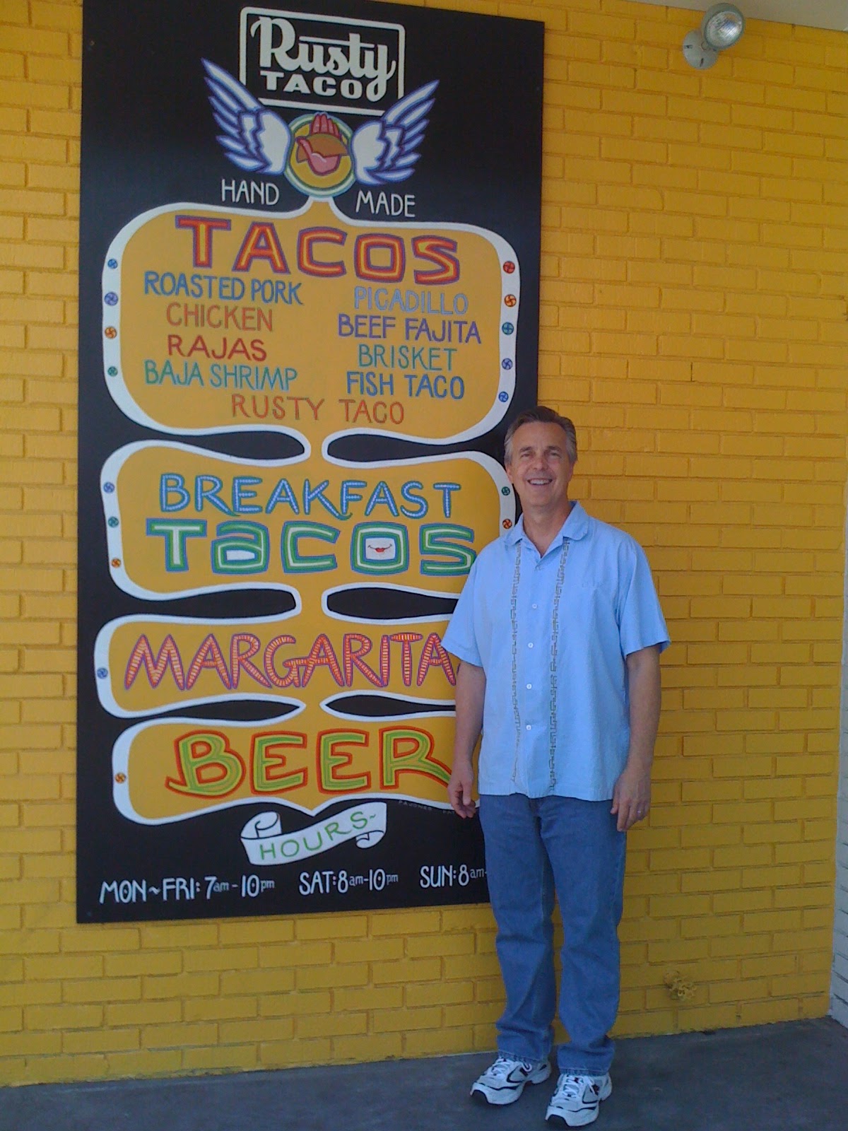 Rusty Fenton standing beside the Rusty Taco menu sign in 2010